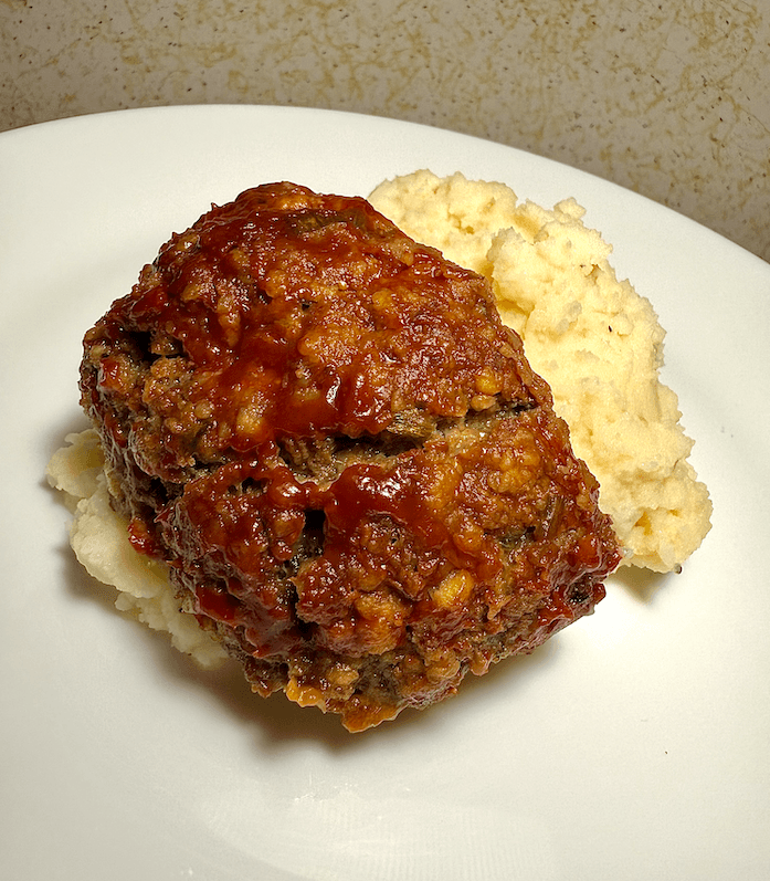 Easy gluten-free and low FODMAP meatloaf sliced and served on a plate with a side of vegetables.